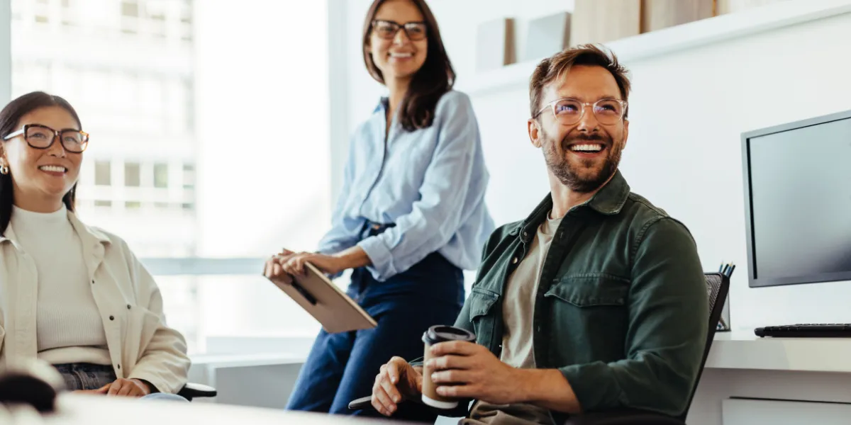 Three smiling colleagues in a bright office during a meeting