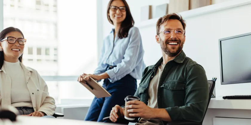 Three smiling colleagues in a bright office during a meeting