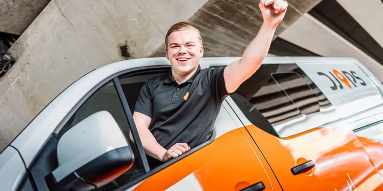A Djops employee cheering from the window of a company van