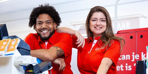 Two Kruidvat staff in red polo shirts at the till