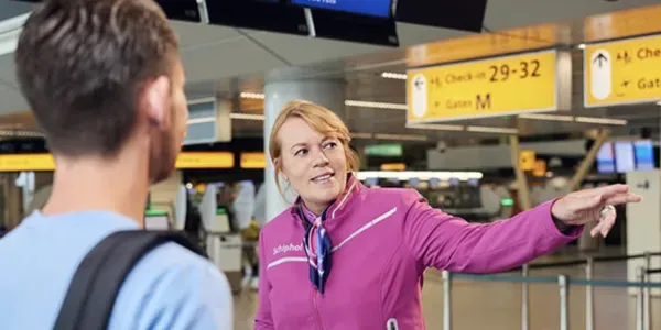 A Schiphol employee pointing a traveller the way in the departures hall